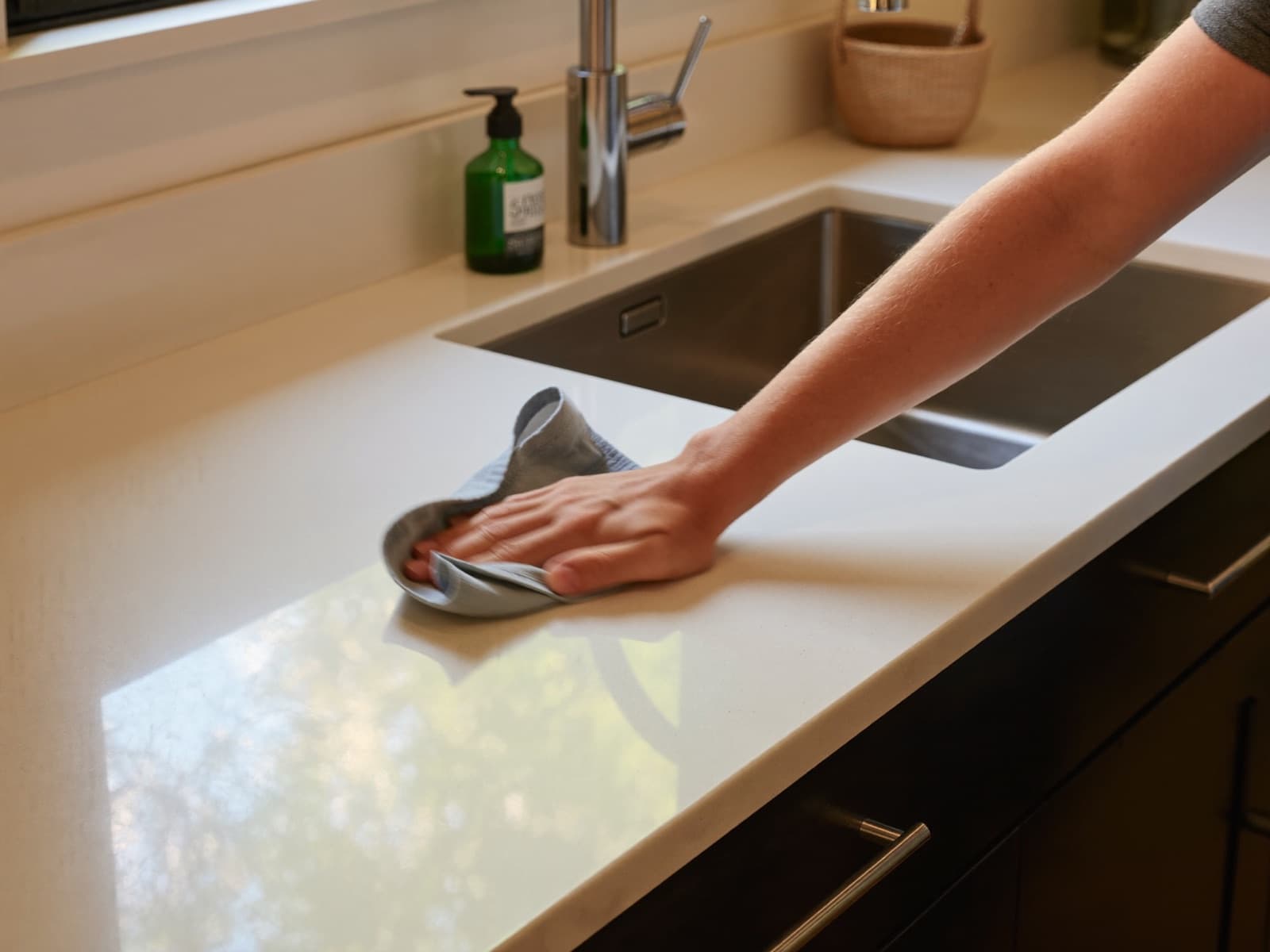 Wiping down a white kitchen countertop with a microfiber cloth